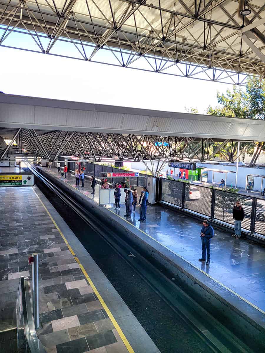 People stand on a platform waiting for a train at a metro station in Mexico City.