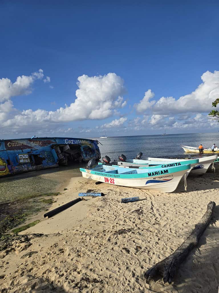 A beach in Cozumel with fishing boats and fishermen cleaning their boats.