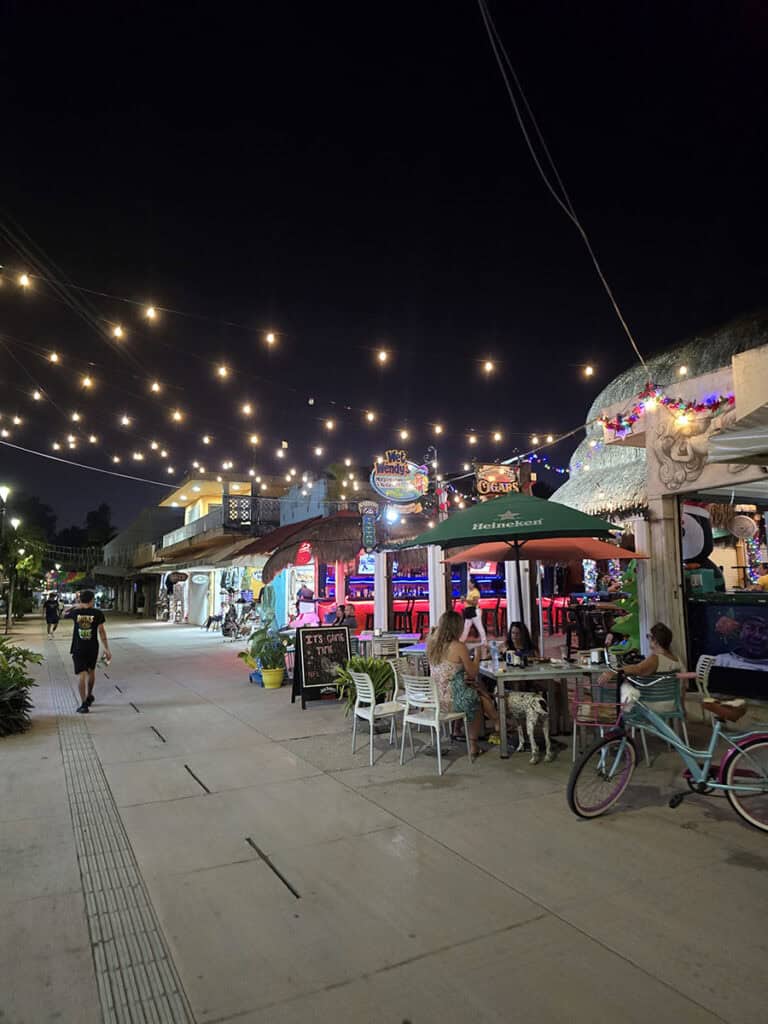Downtown Cozumel at night with people sitting on a bar patio with lights overhead.