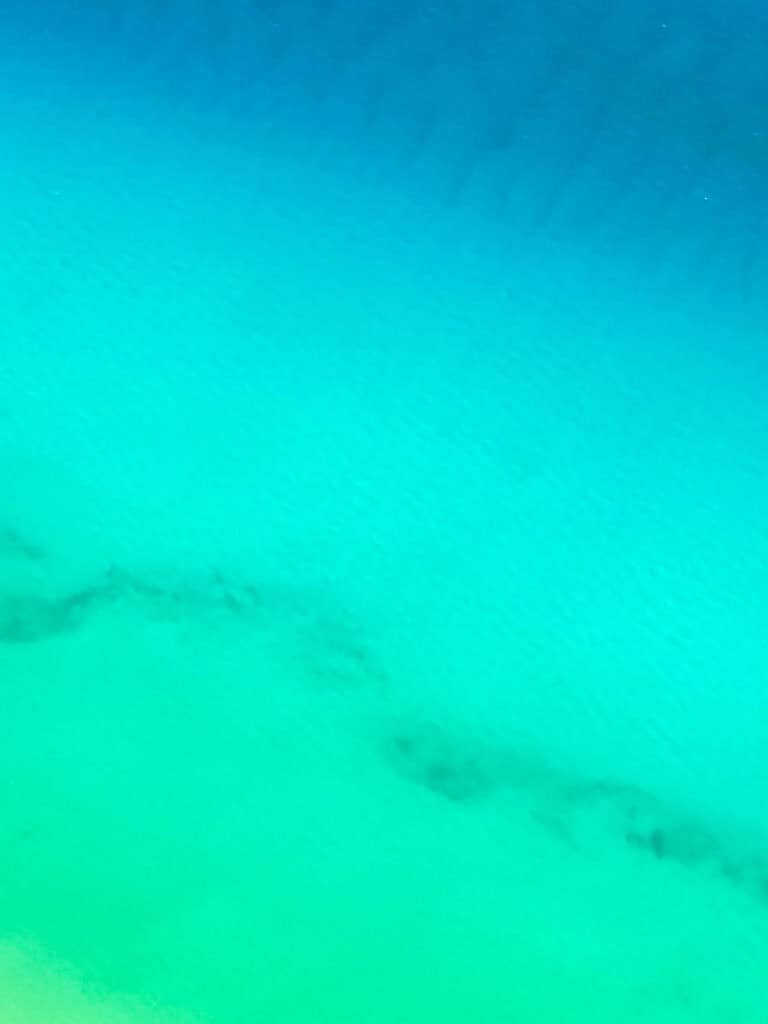 A bird's eye view of the reef at Cozumel with gradient blue to green water.